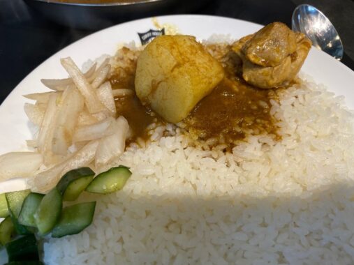 チキンとじゃがいもがカレーと共にライスの上に乗っている